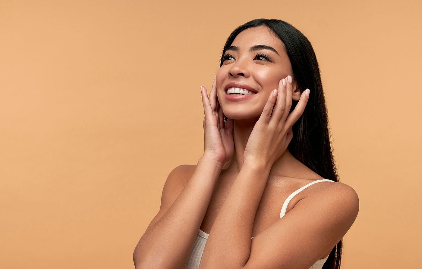 Smiling woman with long hair against orange background.