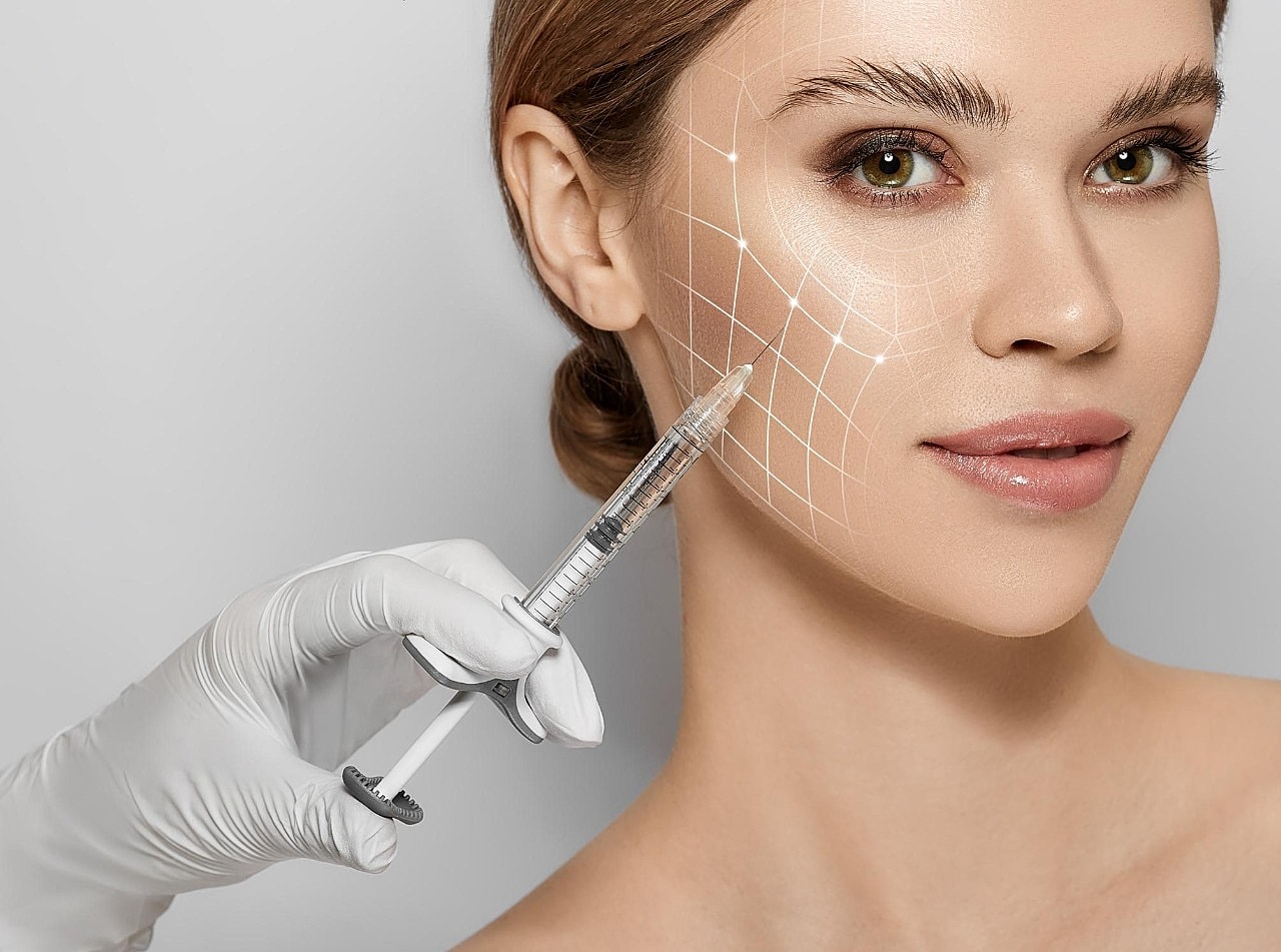 Cosmetic procedure with syringe on woman's face.