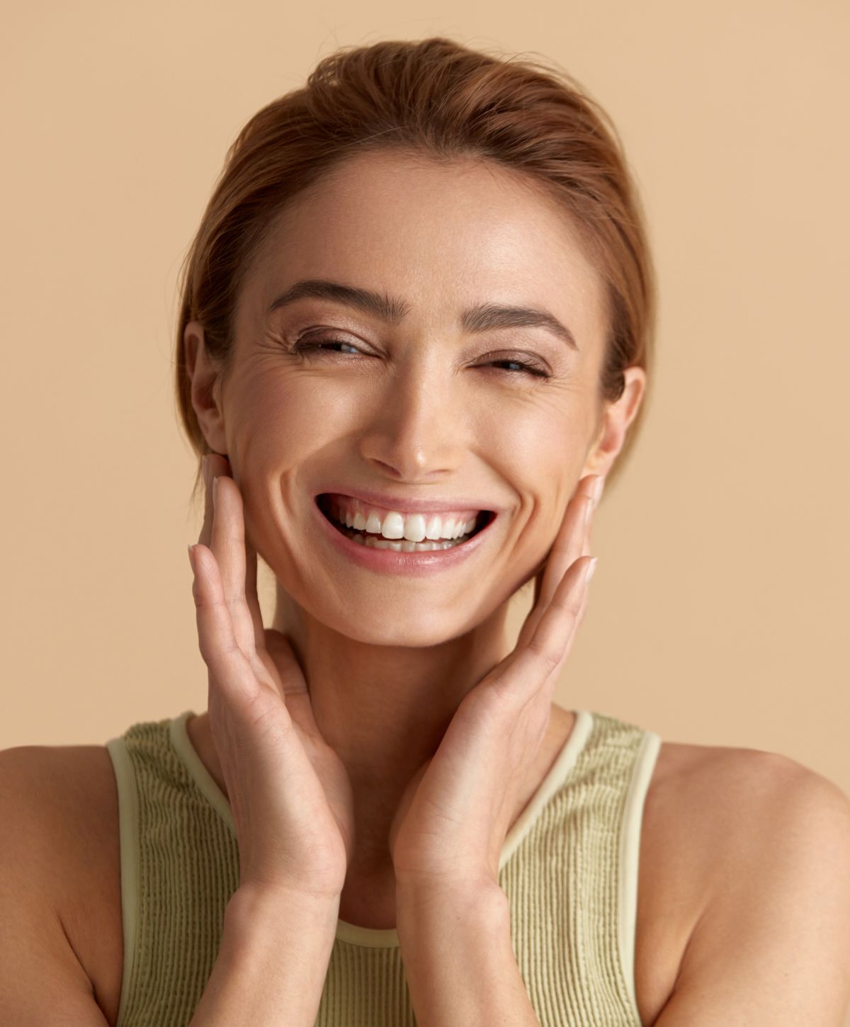 kulift patient model wearing a green tank top smiling while touching her cheeks