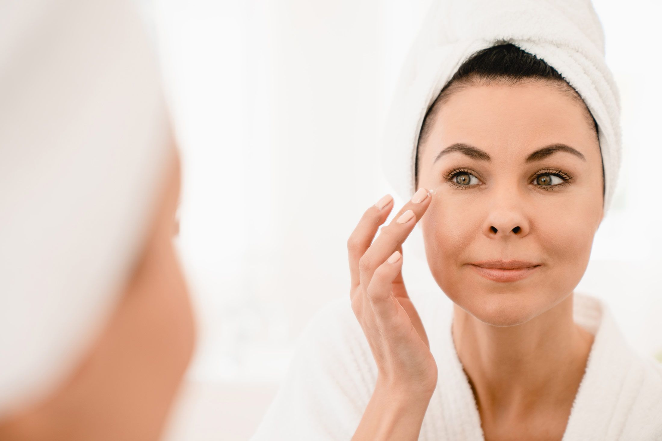 ipl photofacial patient model looking into a mirror with a towel wrapped around her head and a robe