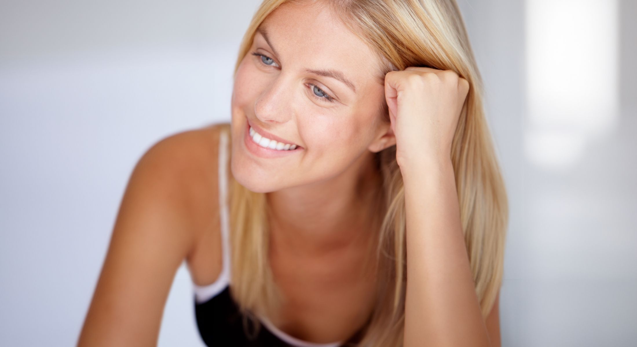 chemical peels patient model smiling wearing a black tank top and resting her head on her fist