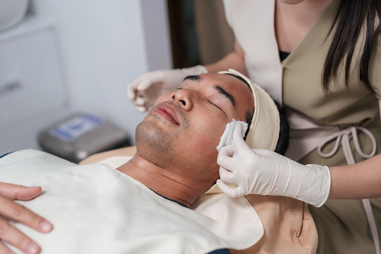 Who Is a Good Candidate for Men’s Skin Treatments in Bellevue?receiving facial treatment in a spa.