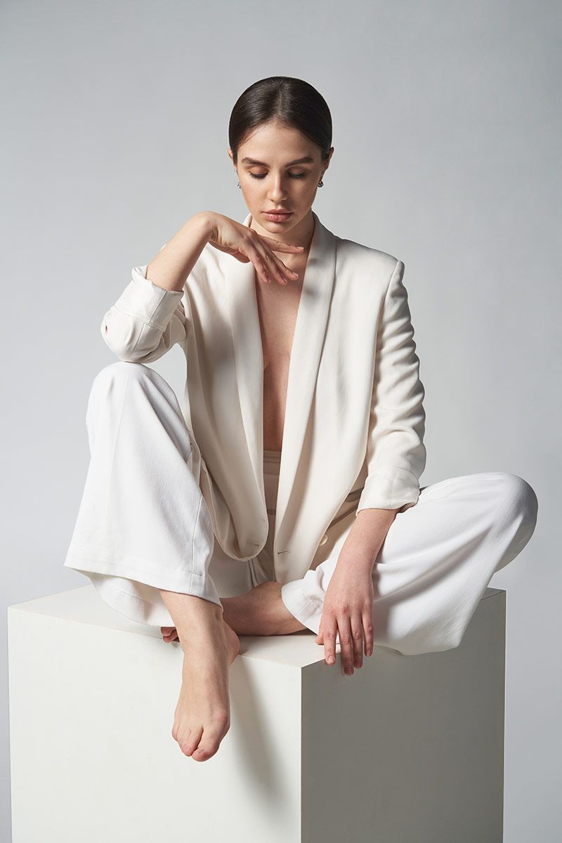 non-surgical feminization patient model in a white robe sitting on a block